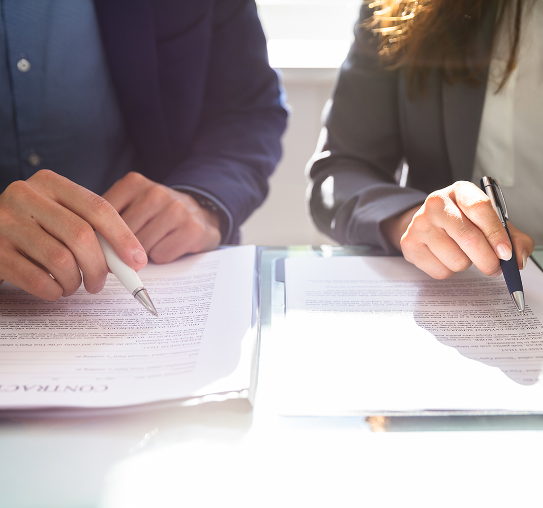 A man and a woman surveying a contracting before signing with pens